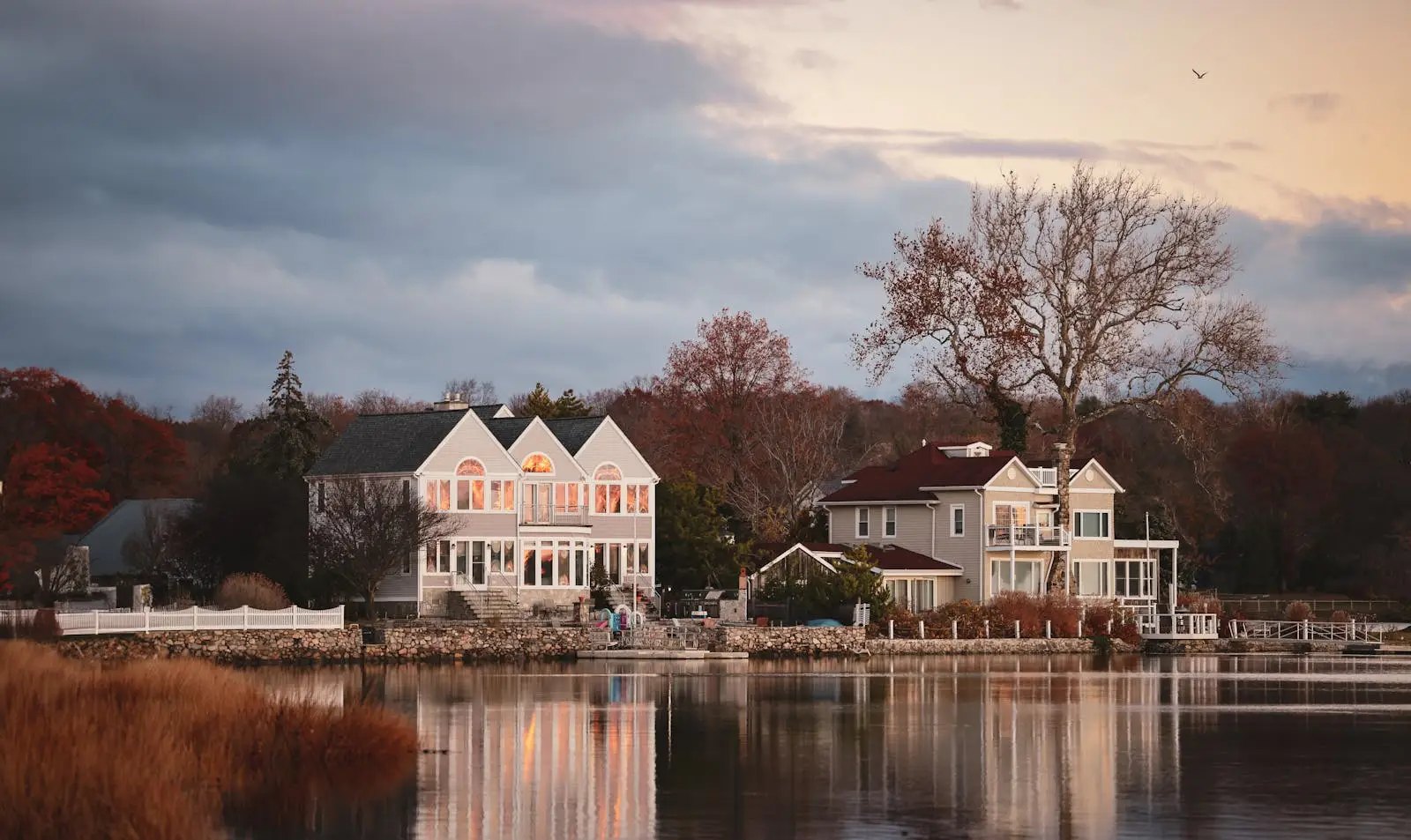 Charming waterfront residences reflecting in a calm lake, captured during a serene autumn evening in bridgeport Connecticut